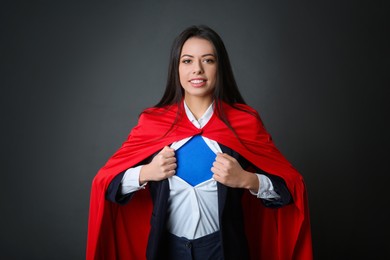 Photo of Confident businesswoman wearing superhero costume under suit on grey background
