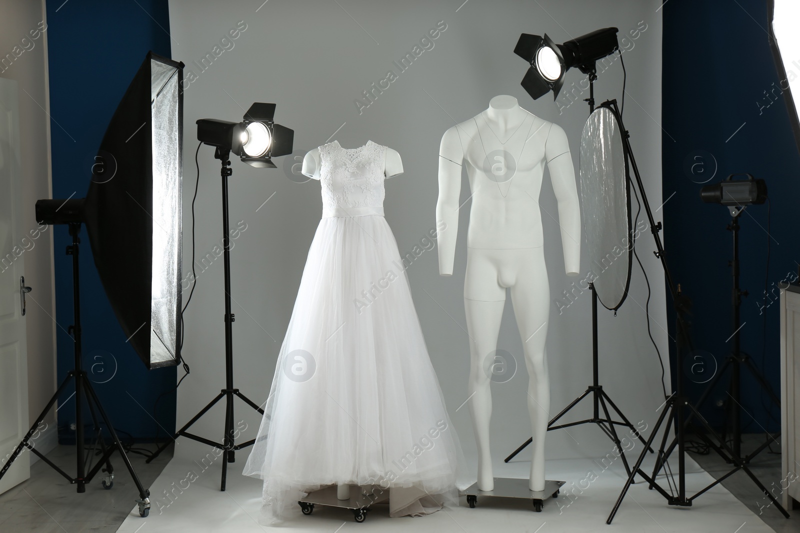 Photo of Beautiful clothes on ghost mannequin and professional lighting equipment in modern studio. Fashion photography