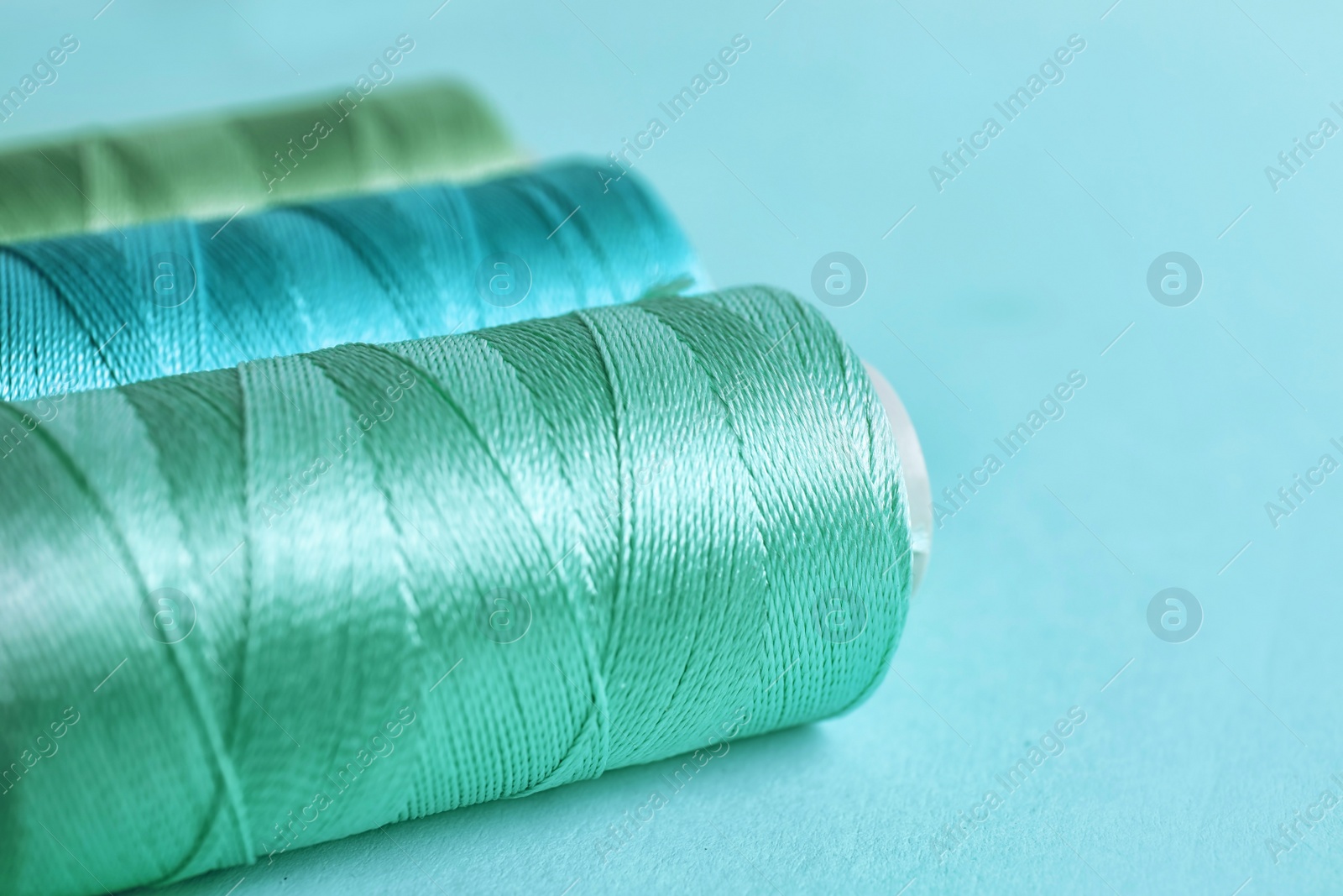 Photo of Mint color sewing threads on table, closeup