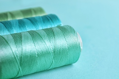 Photo of Mint color sewing threads on table, closeup