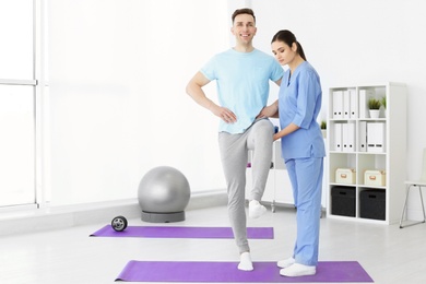 Photo of Physiotherapist working with young male patient in clinic