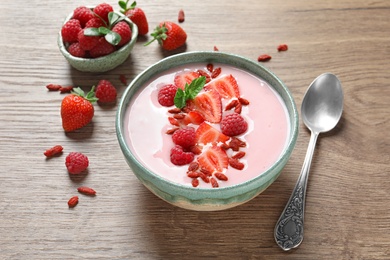 Photo of Smoothie bowl with goji berries and spoon on wooden table