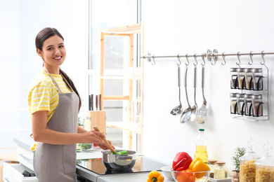 Photo of Young woman cooking tasty soup in kitchen