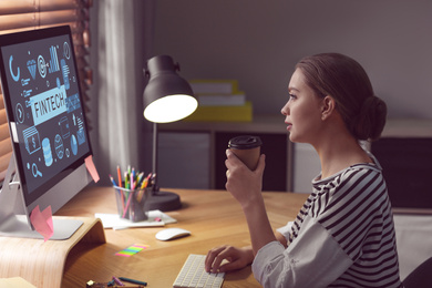 Image of Young woman working on computer at desk in office. Fintech concept