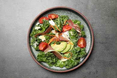 Delicious kale salad with prosciutto served on grey table, top view