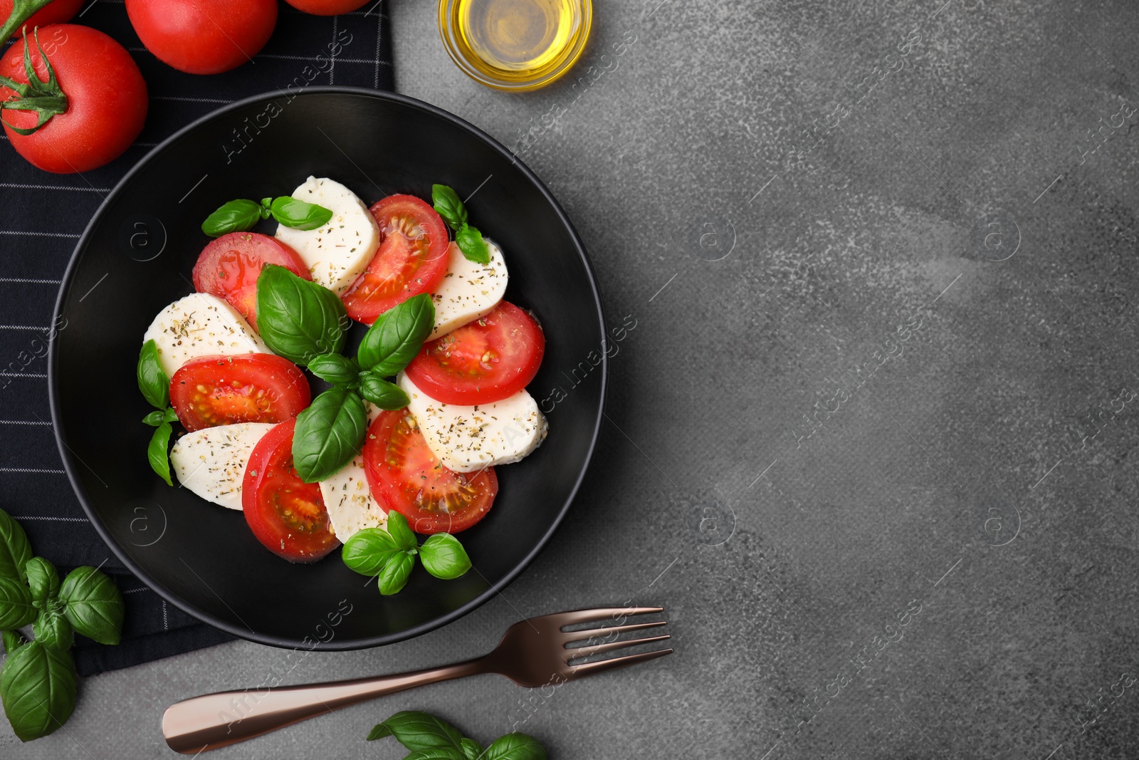 Photo of Delicious salad Caprese with tomatoes, mozzarella, basil and spices served on brown table, flat lay. Space for text