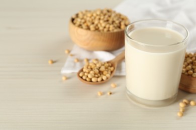 Photo of Soy milk and beans on wooden table, closeup. Space for text