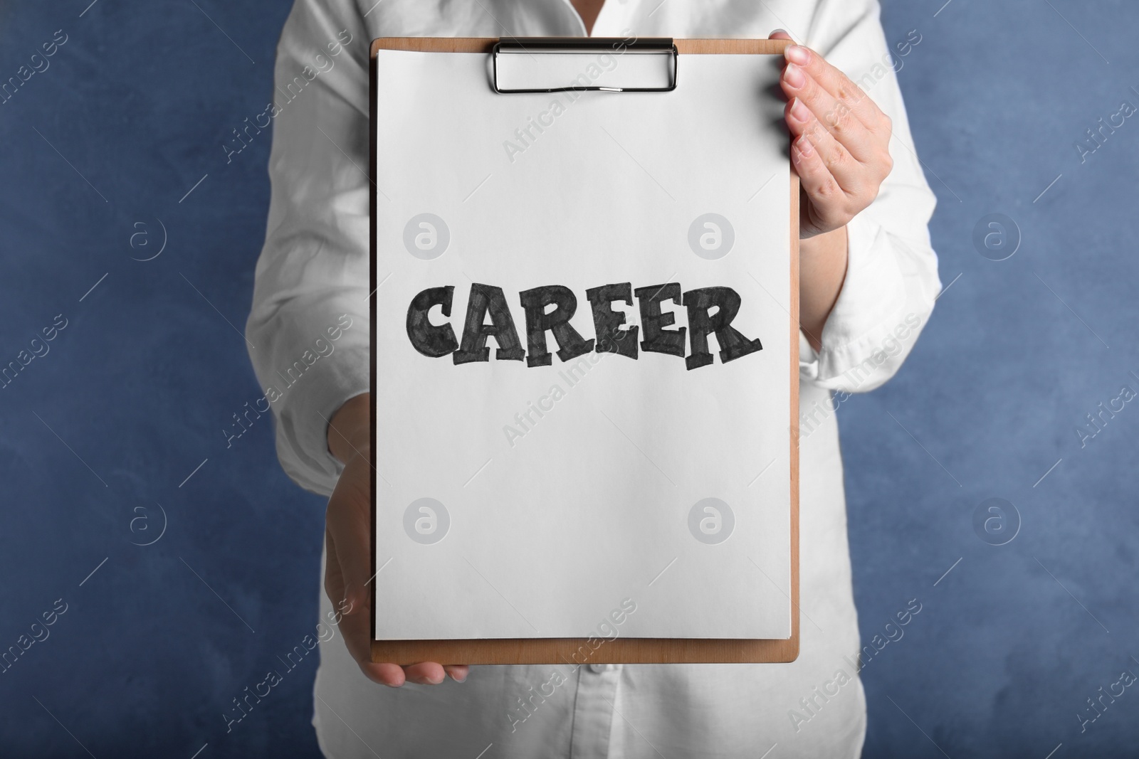 Photo of Woman holding clipboard with word CAREER on blue background, closeup