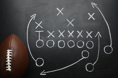 Photo of Rugby ball and drawn American football strategy game on black chalkboard, top view