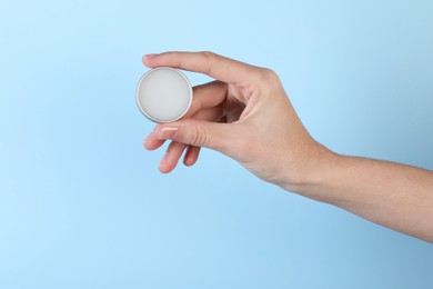 Photo of Woman with lip balm on light blue background, closeup