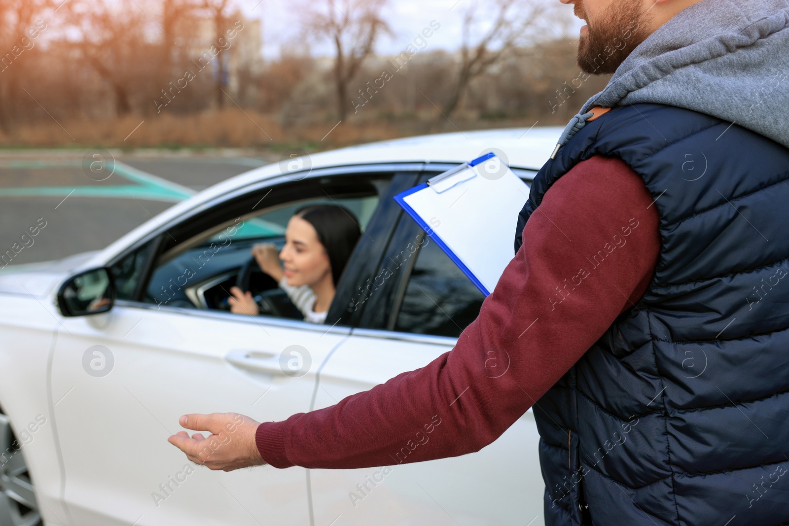 Photo of Instructor near car with his student during exam at driving school test track