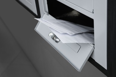 Photo of Open metal mailbox with envelopes indoors, closeup view
