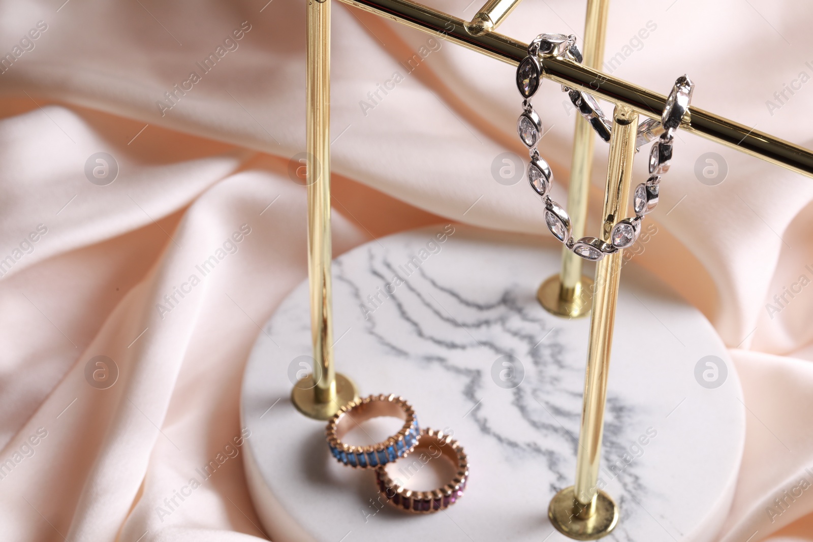 Photo of Elegant jewelry. Stylish presentation of luxury bracelet and rings on holder, space for text