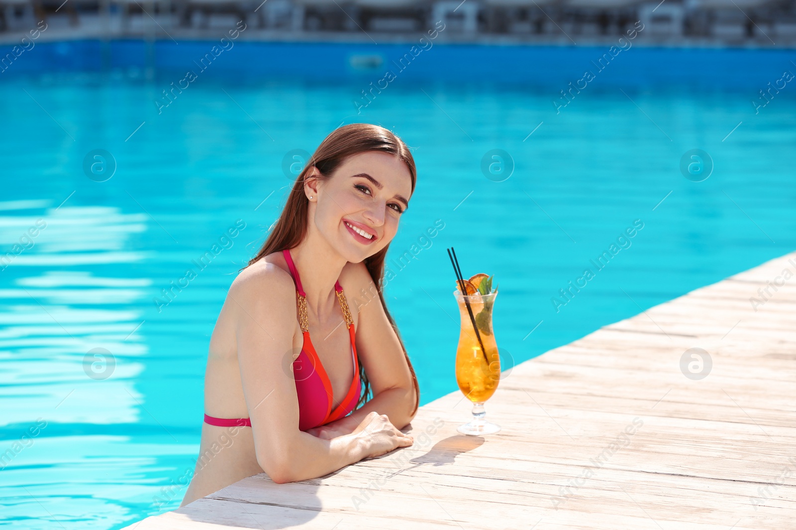 Photo of Beautiful young woman with cocktail in swimming pool