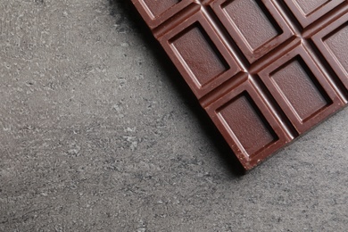 Chocolate bar on grey background, top view. Space for text