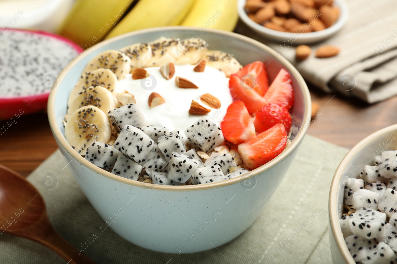 Photo of Bowl of granola with pitahaya, banana, strawberries and yogurt on table