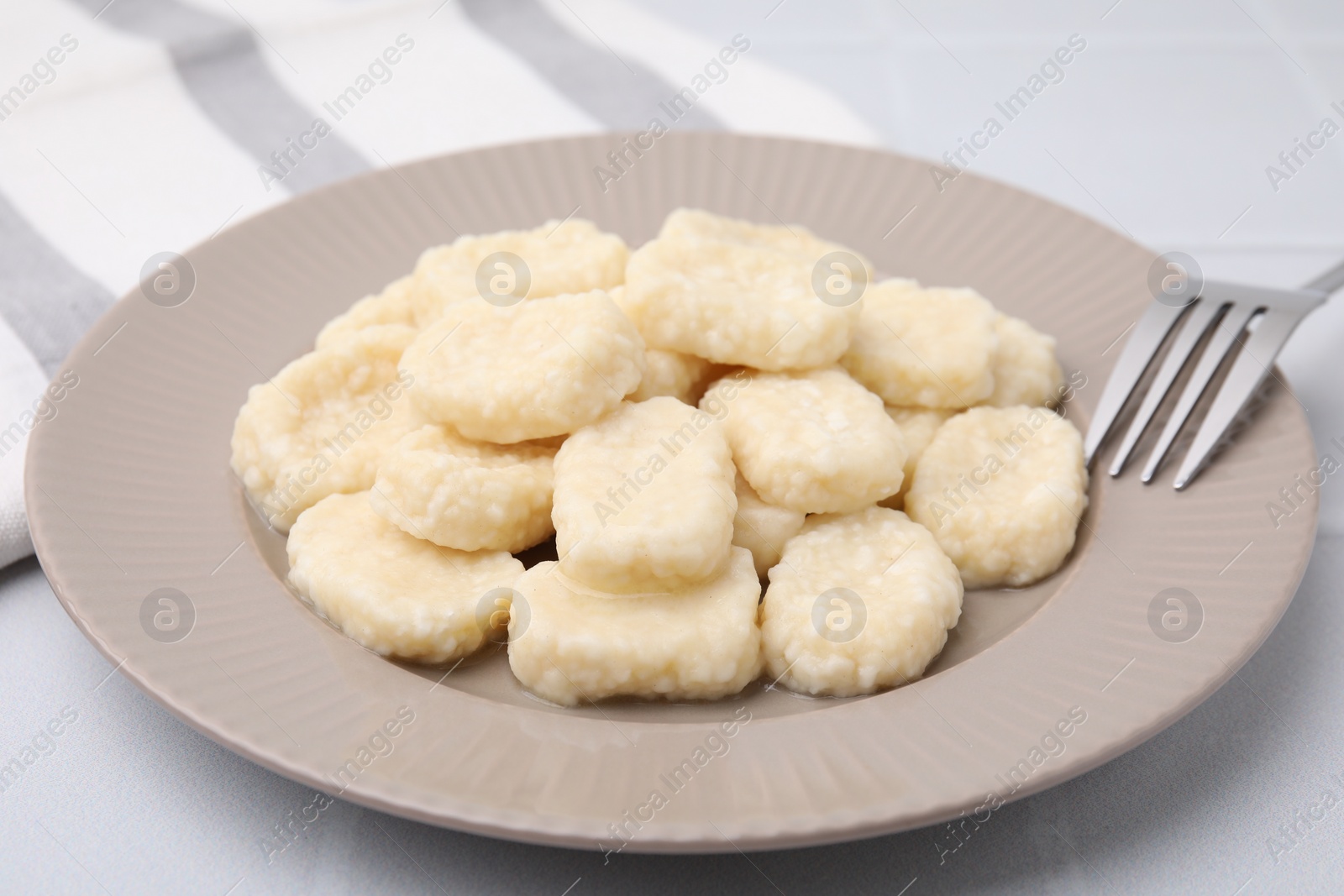 Photo of Plate of tasty lazy dumplings on white table, closeup