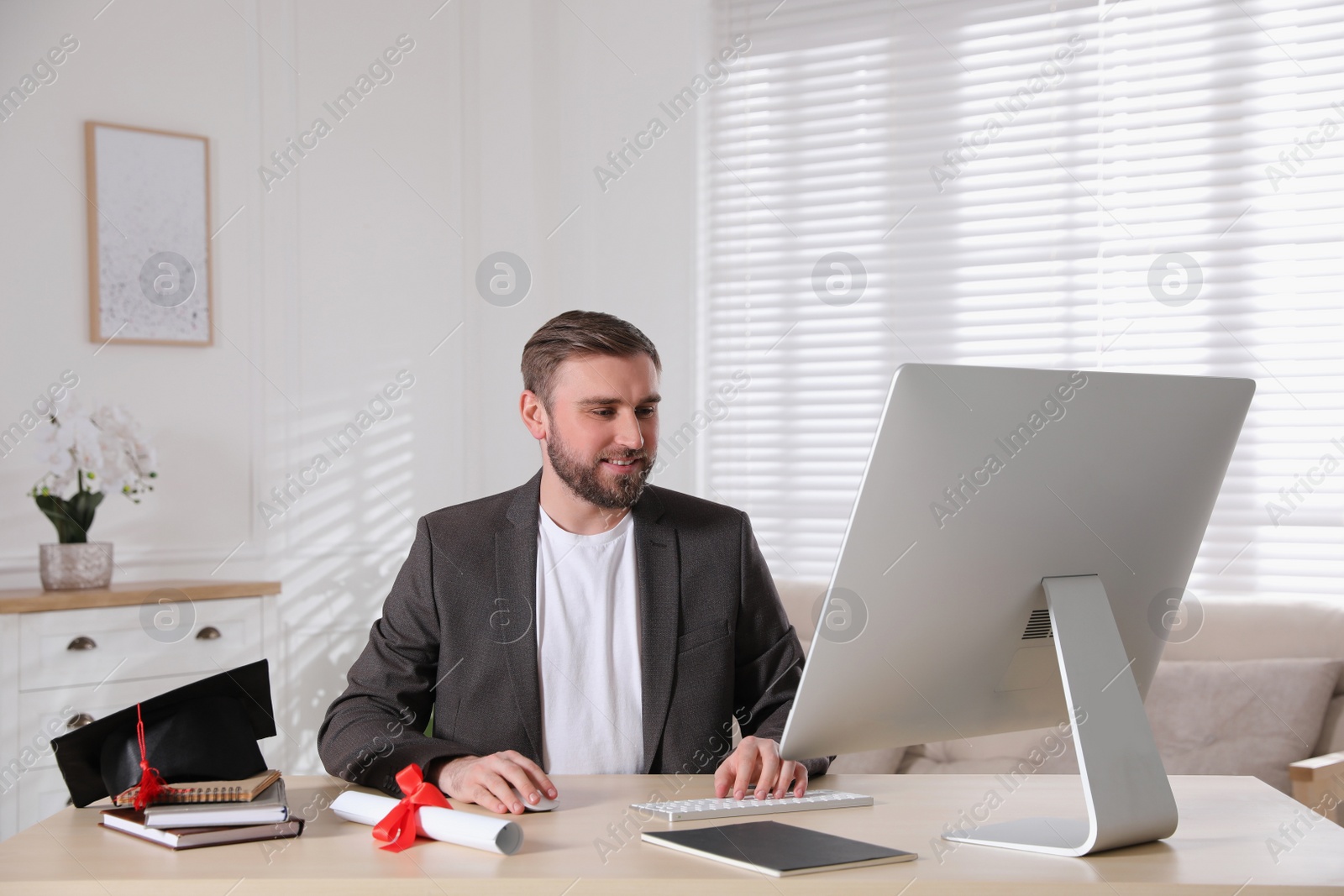 Photo of Happy student with graduation hat and diploma at workplace in office