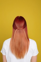 Woman with bright dyed hair on yellow background, back view