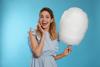 Photo of Portrait of pretty young woman with cotton candy on blue background