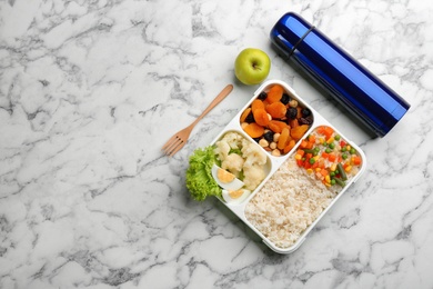 Thermos and lunch box with food on white marble, flat lay. Space for text