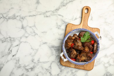 Bowl with delicious kidneys, pepper and parsley on white marble table, top view. Space for text