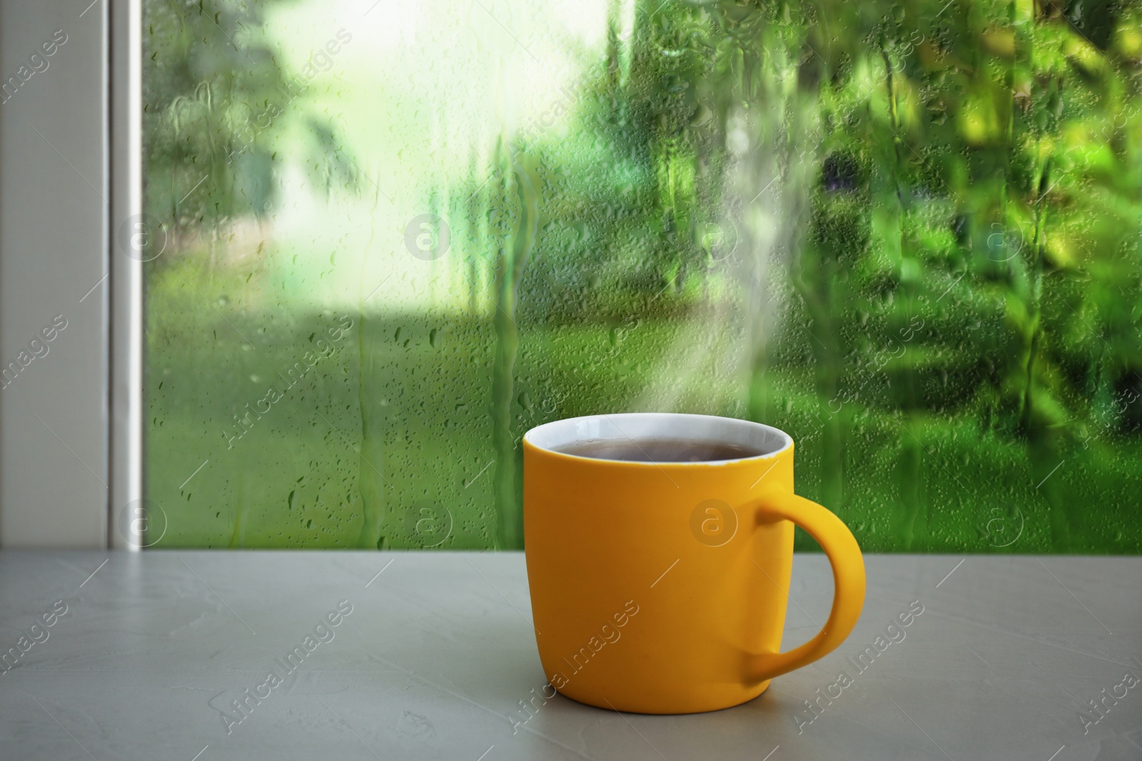 Image of Cup of hot drink near window on rainy day