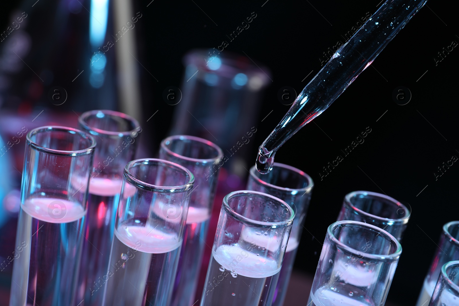 Photo of Dripping reagent into test tube on black background, closeup. Laboratory analysis