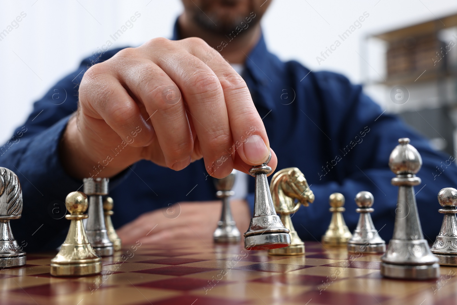 Photo of Man with game piece playing chess at checkerboard indoors, closeup