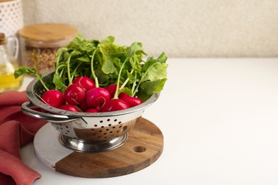 Wet radish in colander on white table, closeup. Space for text