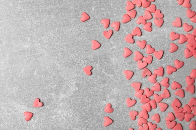 Photo of Pink heart shaped sprinkles on grey table, flat lay. Space for text