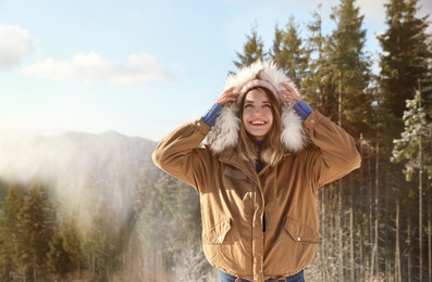 Happy young woman spending winter vacation in mountains