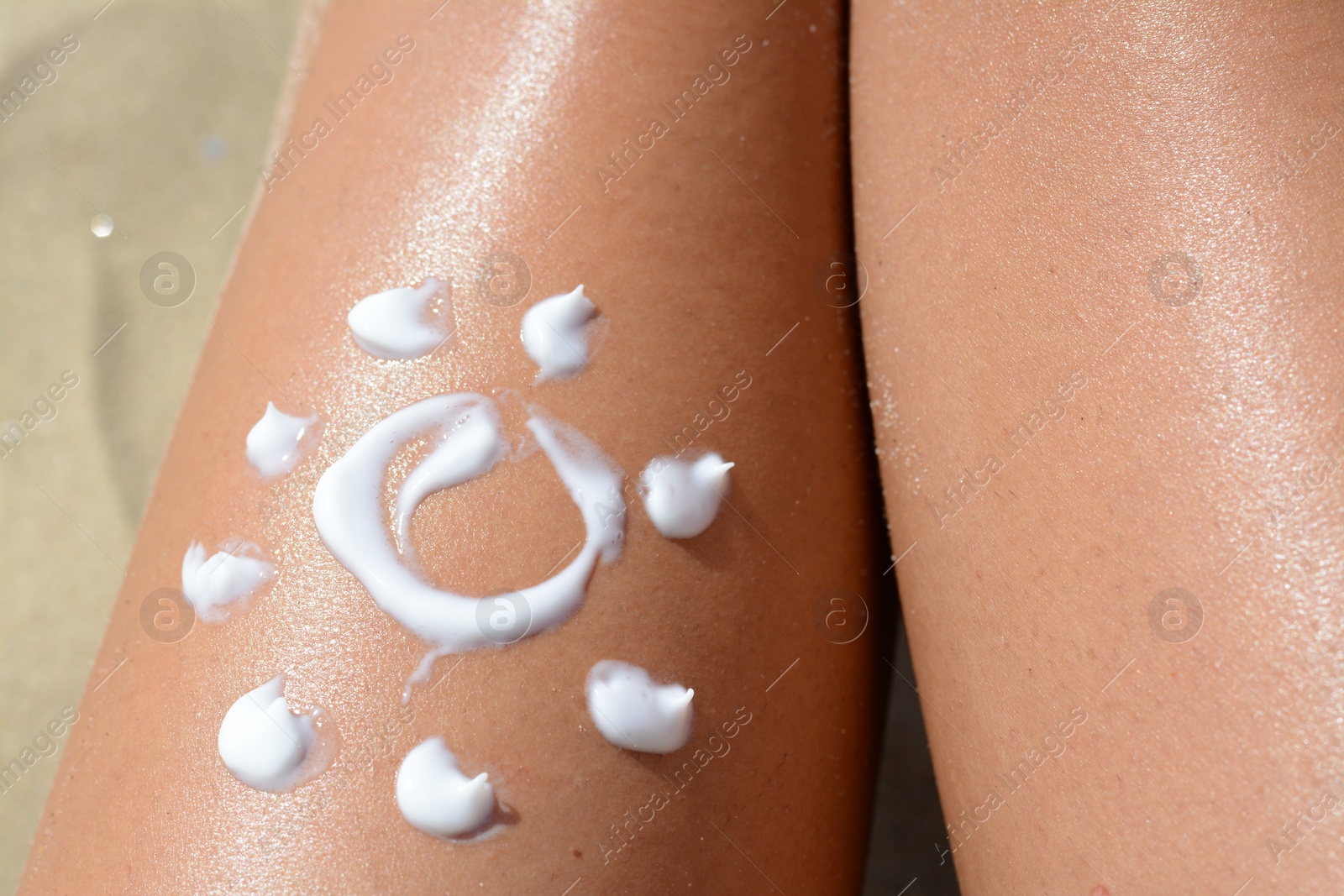 Photo of Sun drawn with sunscreen on woman's leg at beach, closeup