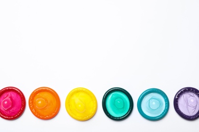 Photo of Colorful condoms on white background, top view. LGBT concept