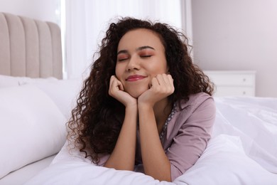 Happy African American woman lying on bed at home
