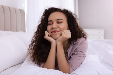 Photo of Happy African American woman lying on bed at home