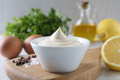 Tasty mayonnaise sauce in bowl, spices and ingredients on table, closeup