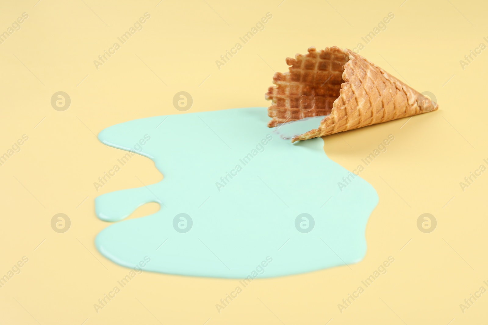 Photo of Melted ice cream and wafer cone on beige background