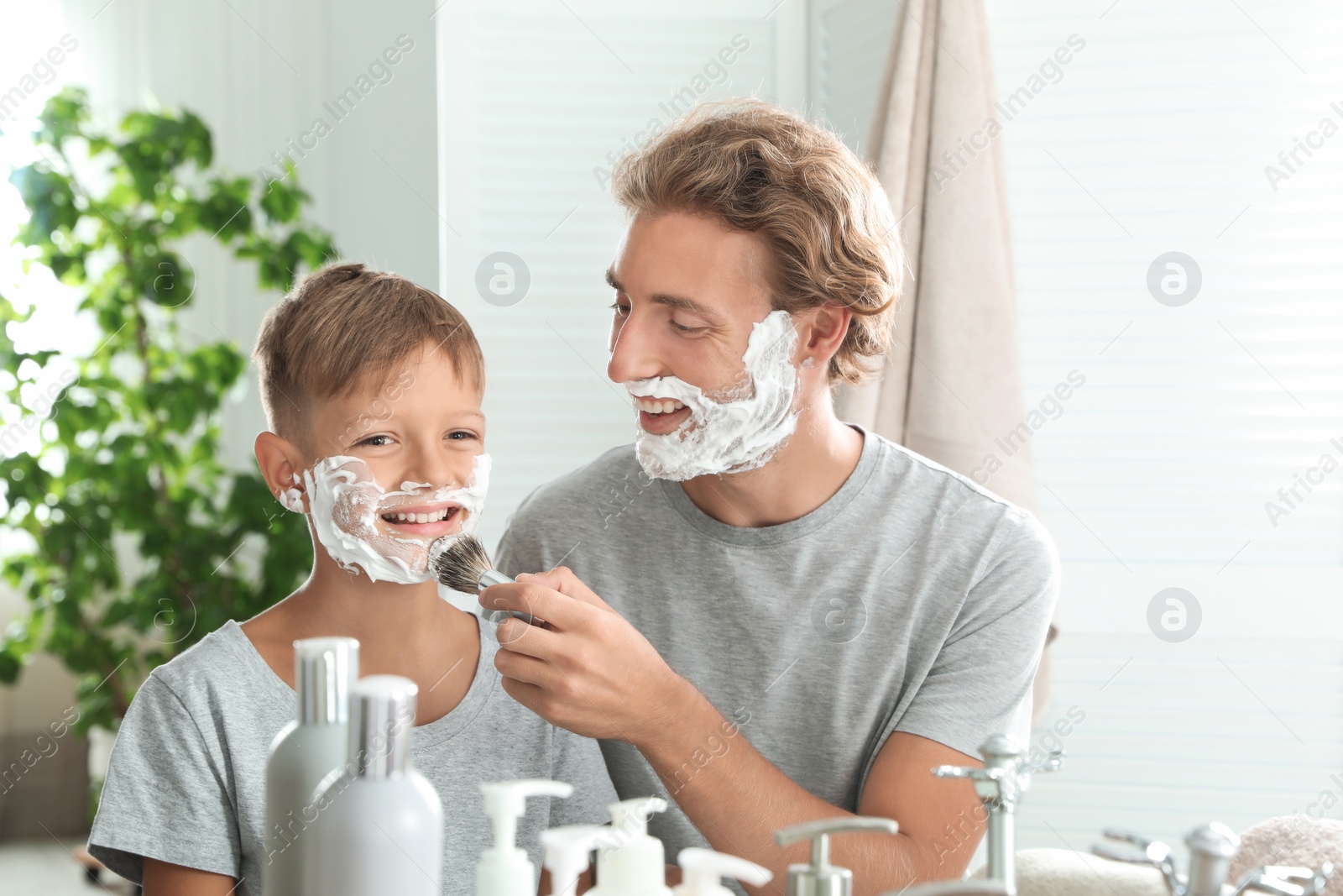 Photo of Father and son shaving together in bathroom