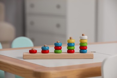 Photo of Stacking and counting game wooden pieces on table indoors, space for text. Educational toy for motor skills development