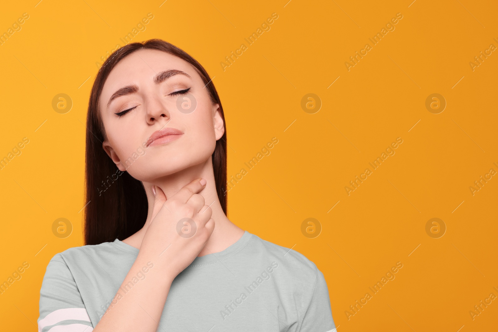 Photo of Young woman with sore throat on orange background. Space for text