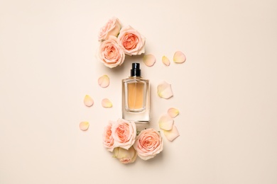 Photo of Flat lay composition with bottle of perfume and roses on light background