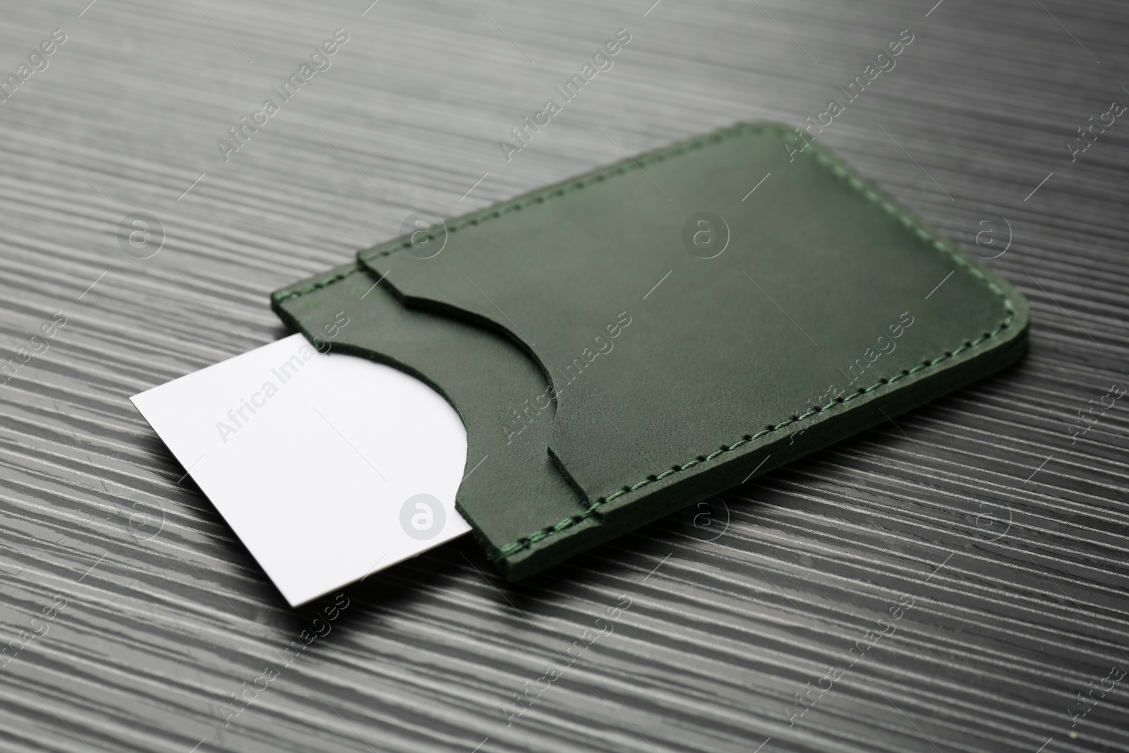 Photo of Leather business card holder with card on grey table, closeup