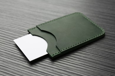 Photo of Leather business card holder with card on grey table, closeup