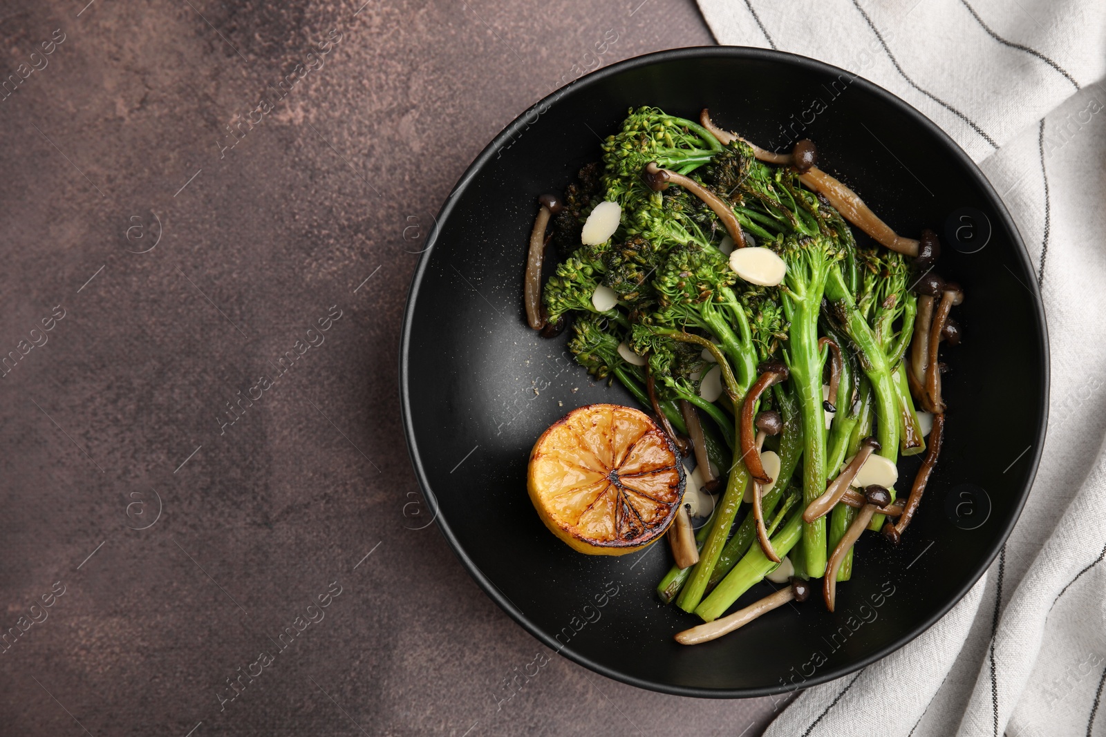 Photo of Tasty cooked broccolini with lemon and mushrooms on grey table, top view. Space for text