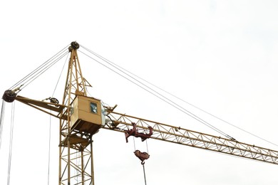 Photo of Tower crane under cloudy sky, low angle view. Construction site