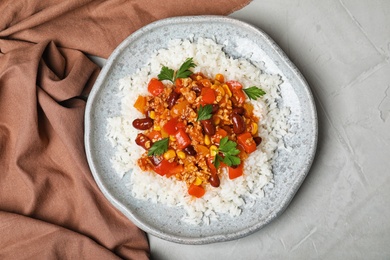 Photo of Plate of rice with chili con carne on gray background, top view