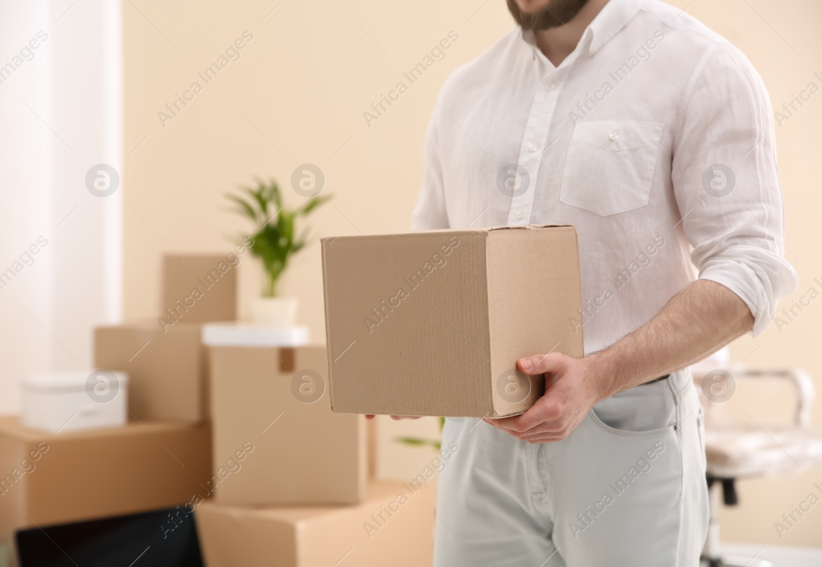 Photo of Man holding moving box in new office, closeup. Space for text