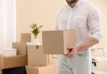 Man holding moving box in new office, closeup. Space for text