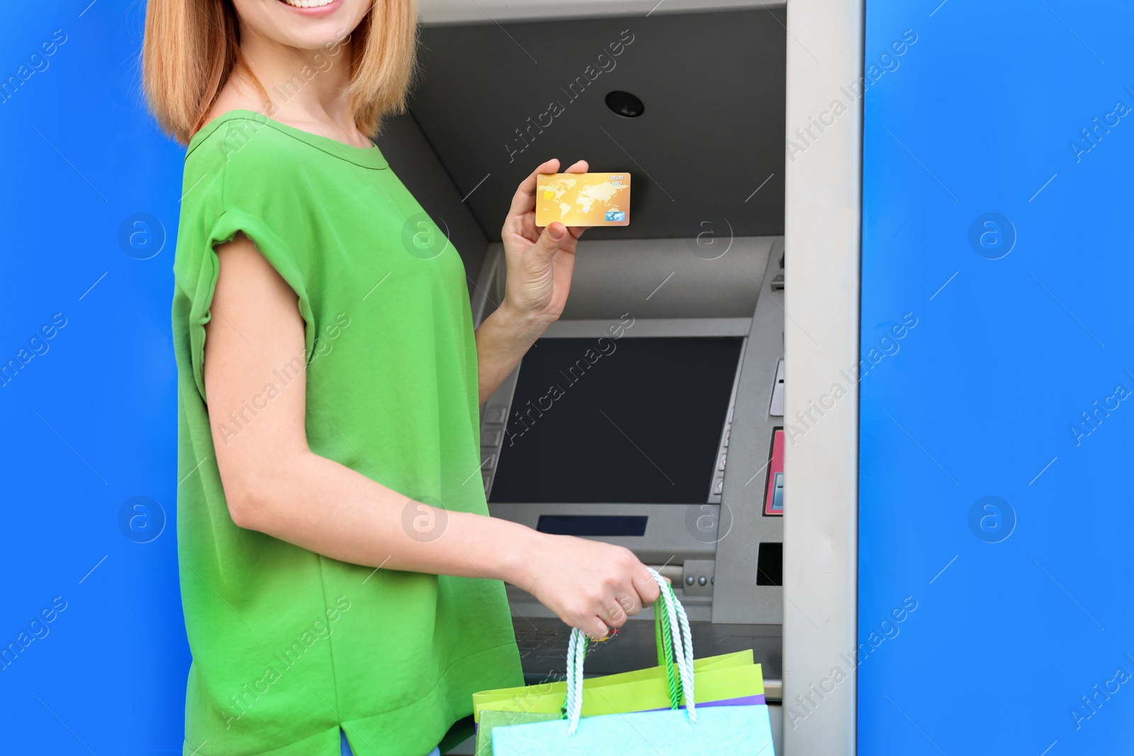 Photo of Woman with credit card near cash machine outdoors, closeup